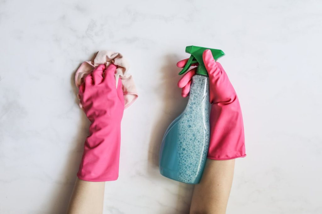 Mastering the First Impression: Your intriguing post title goes here A pair of hands in pink gloves are cleaning with a spray bottle on a white background.